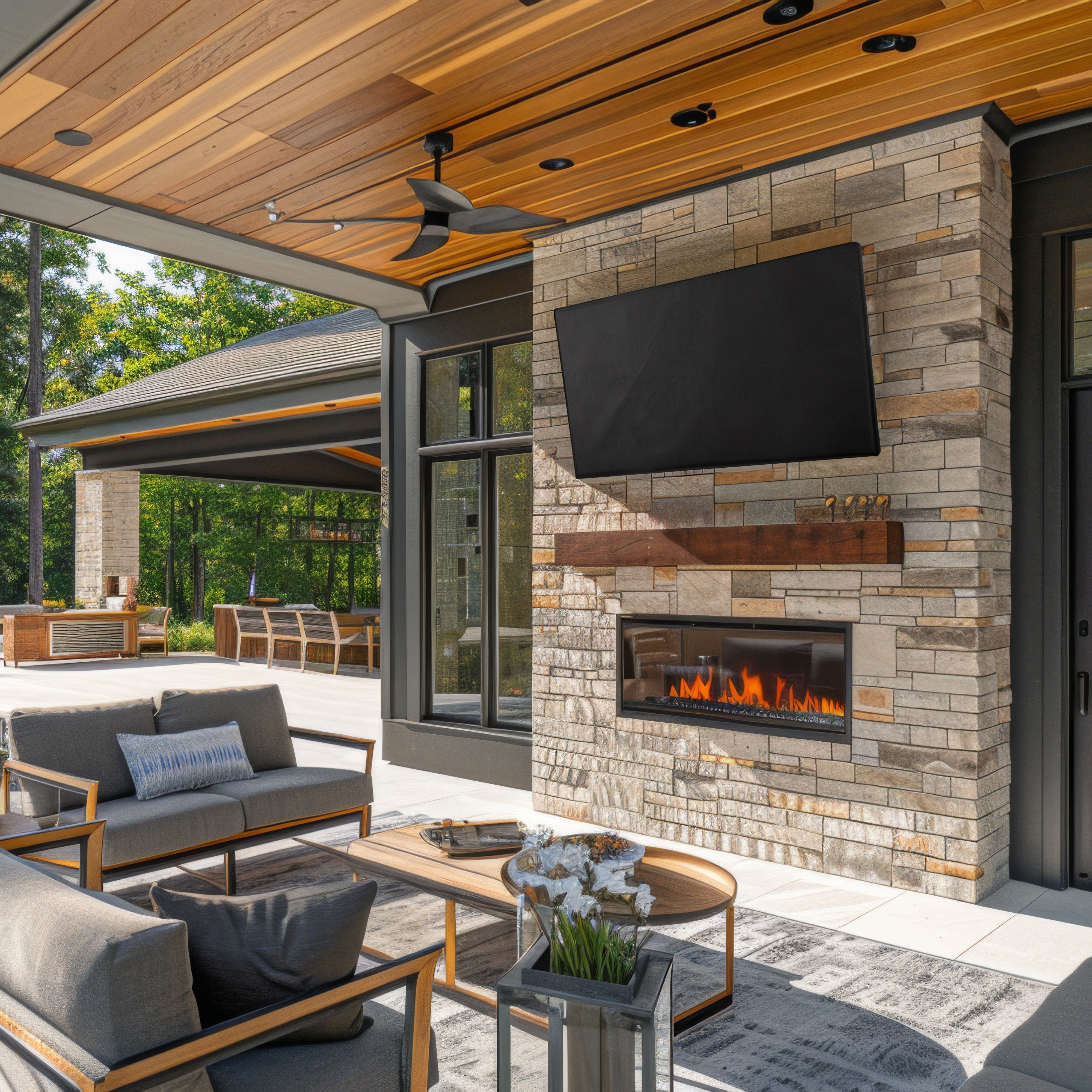 TV with TV cover on stone fireplace in outdoor setting.