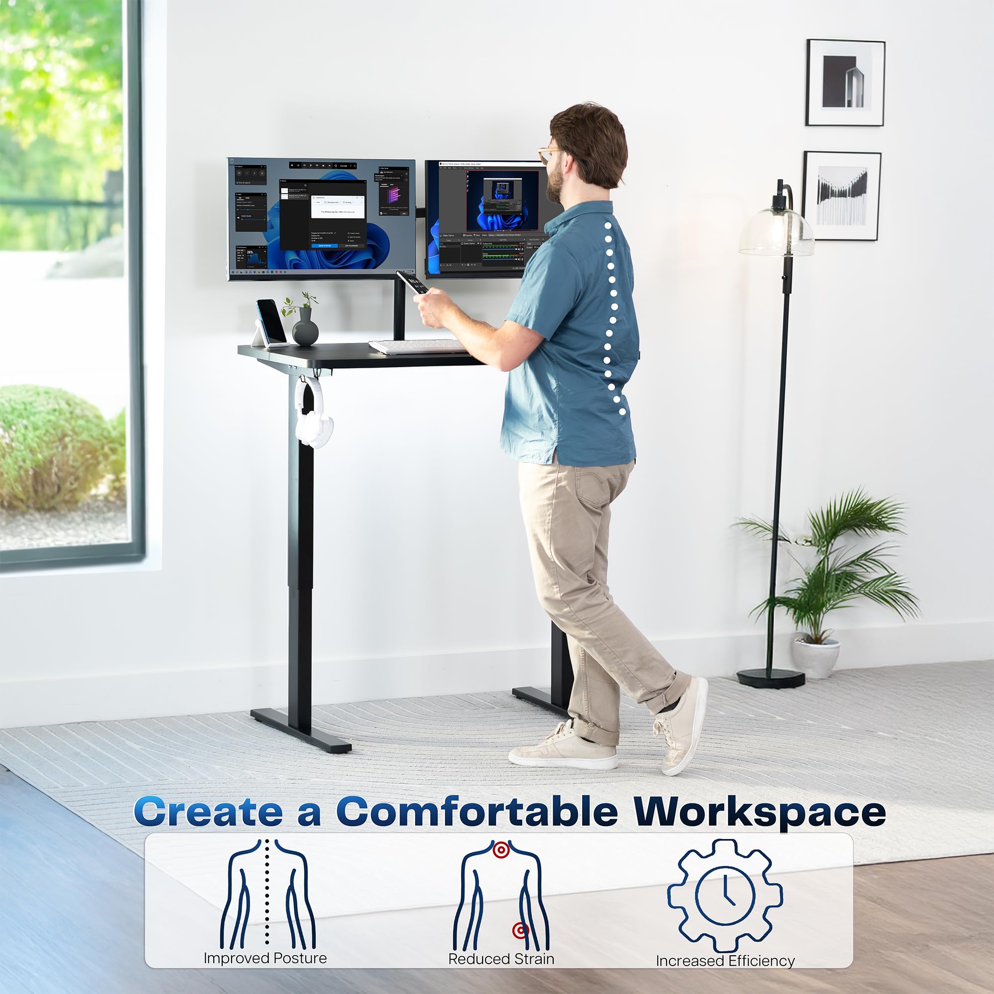 Person using a standing desk in a bright room with plants and a window.