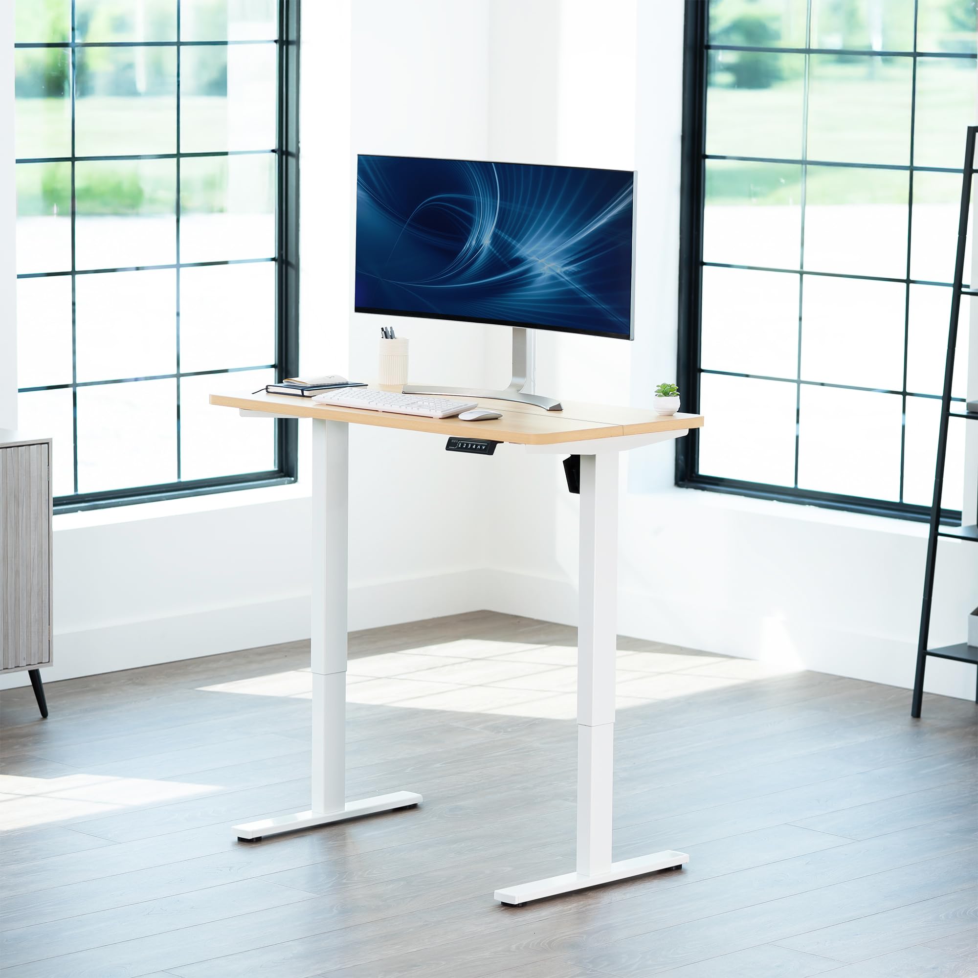Modern office setup with a standing desk and computer monitor in a bright office space.