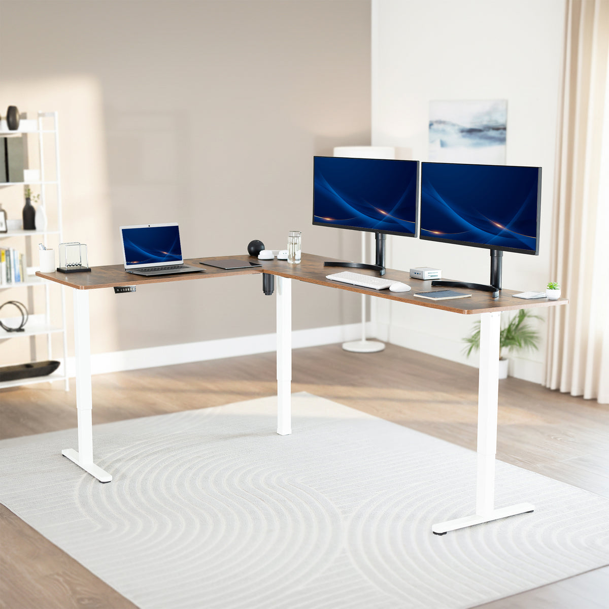 An L-shaped standing desk with a rustic vintage brown top and white metal legs, styled in a modern home office with dual computer monitors, a laptop, and desk accessories.