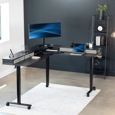 Large dual tier height adjustable electric corner desk with storage drawers and wheels.