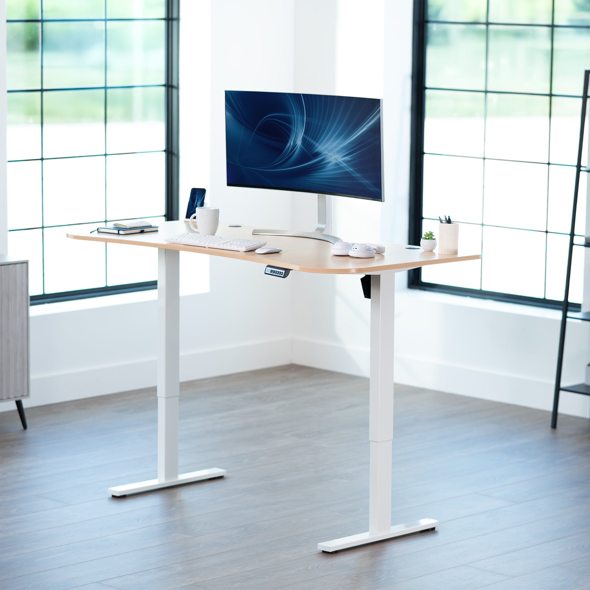 Light wood top white frame, electric, sit to stand, height adjustable desk in office setting.