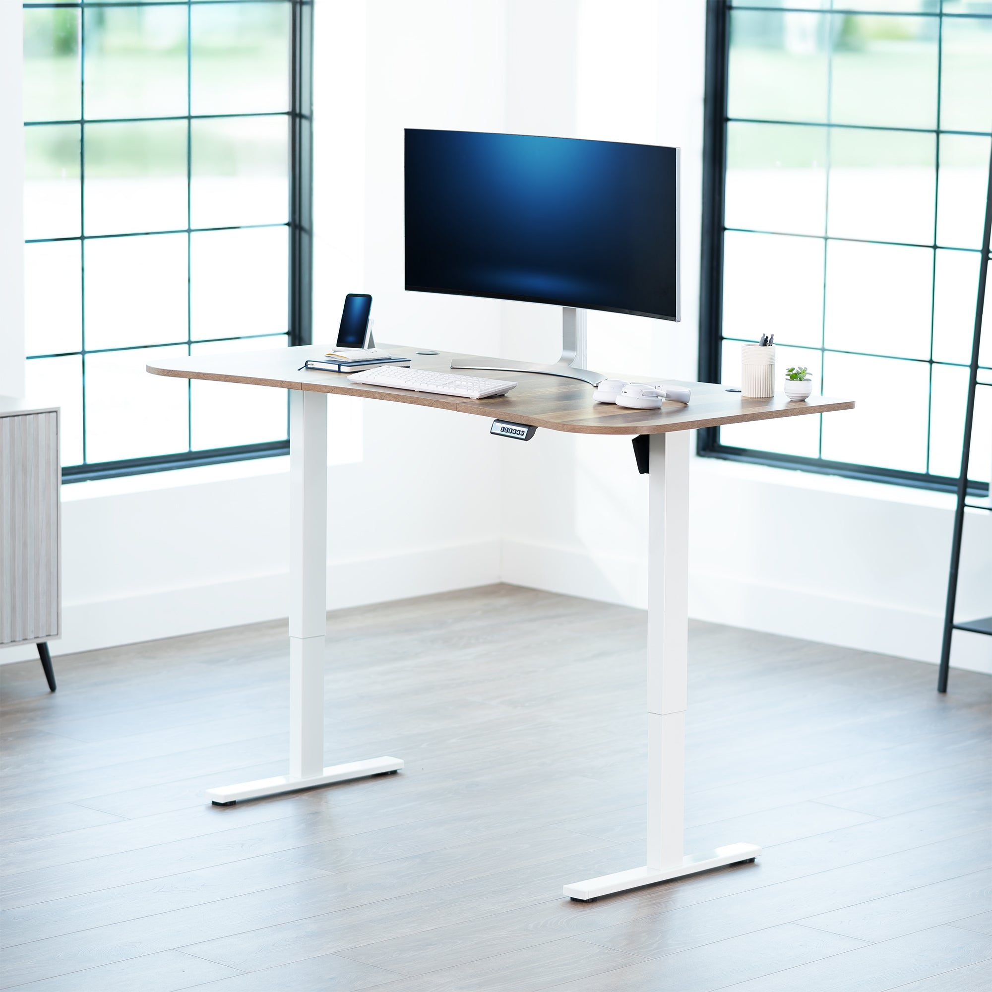 Reclaimed wood top white frame, electric, sit to stand, height adjustable desk in office setting.
