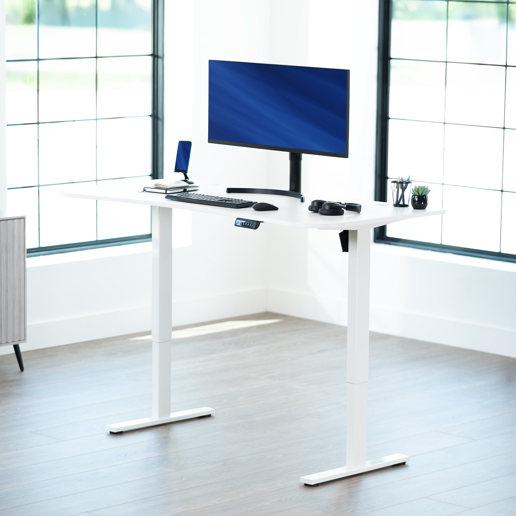 White top white frame, electric, sit to stand, height adjustable desk in office setting.