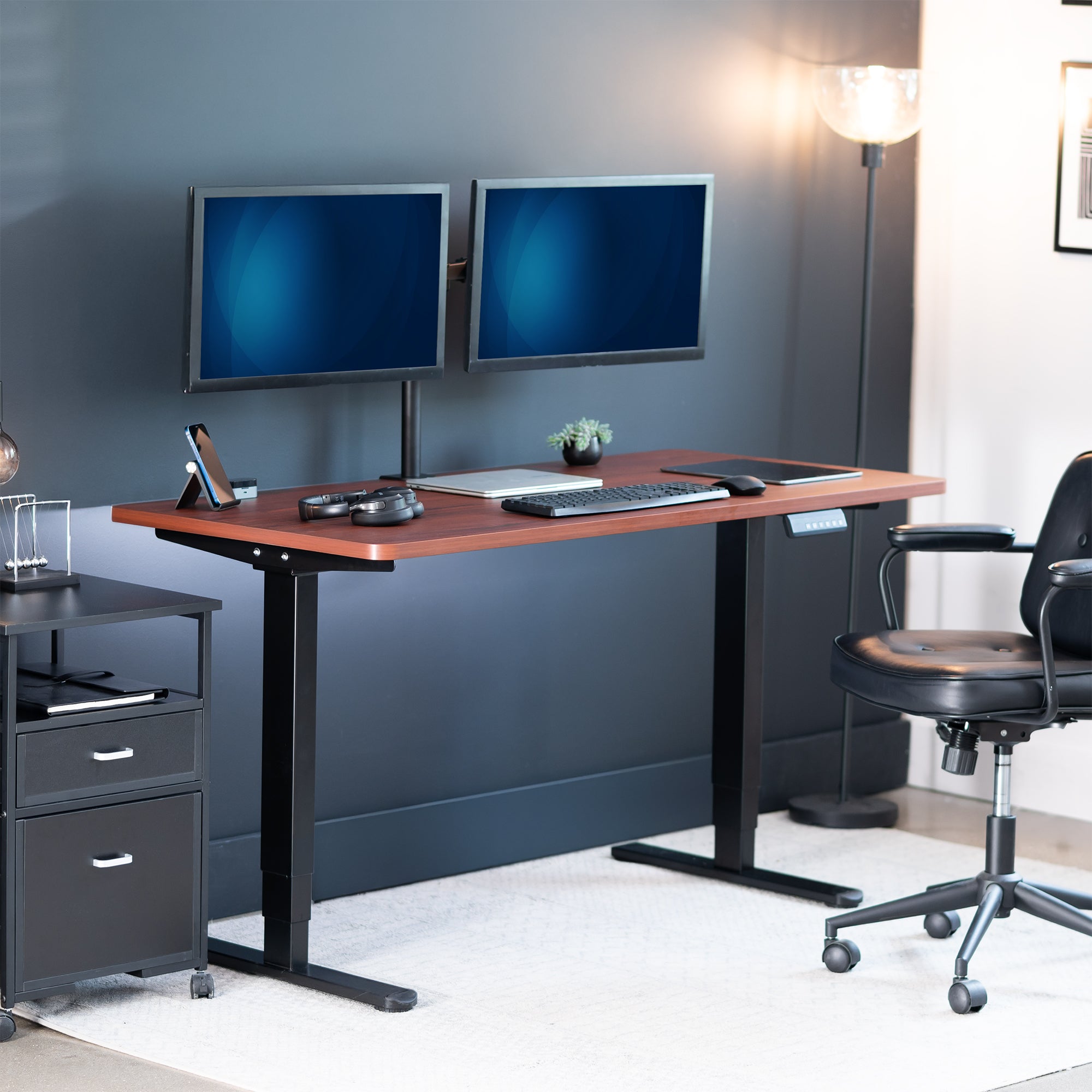 Modern office setup with a standing desk, computer monitors, and chair.