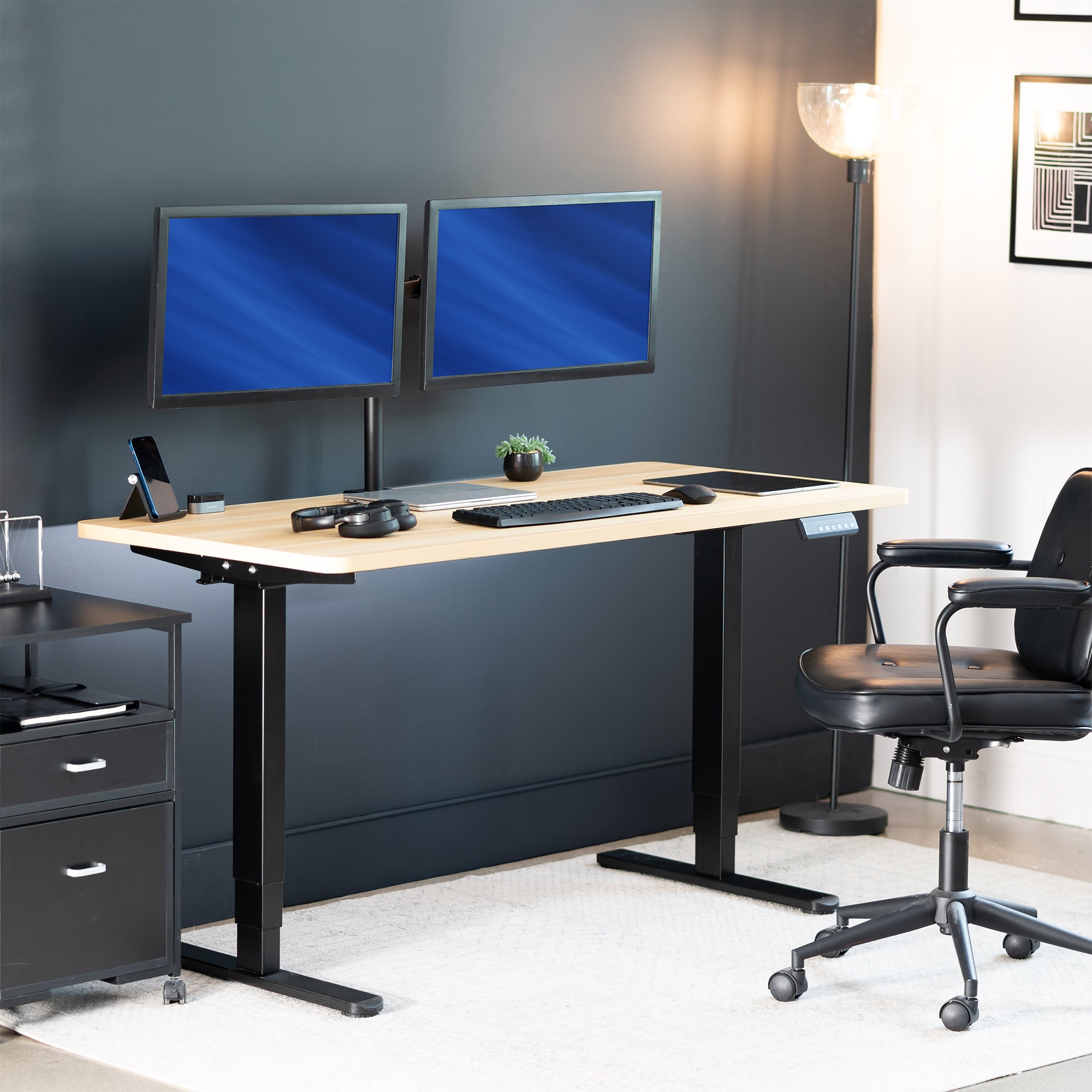 Modern office setup with a standing desk, dual monitors, and office chair.