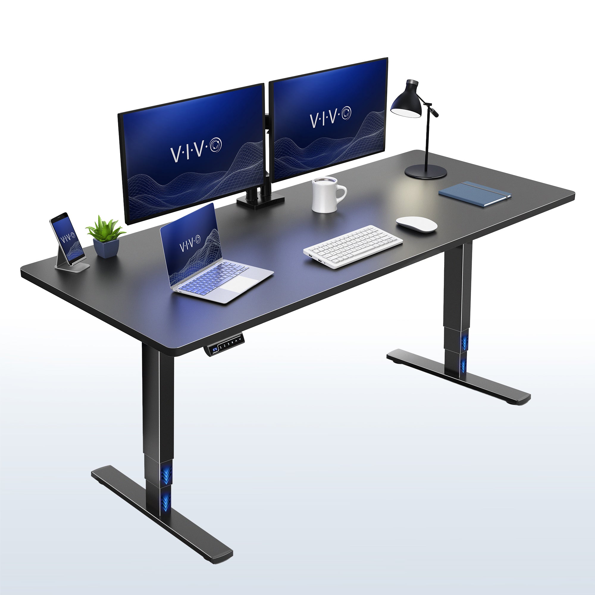 A black modern electric height-adjustable desk with a sleek metal T-style base. The desk is styled with a dual-monitor setup, a laptop, a smartphone on a charging stand, a small potted plant, a white mug, a keyboard, a mouse, and a desk lamp.