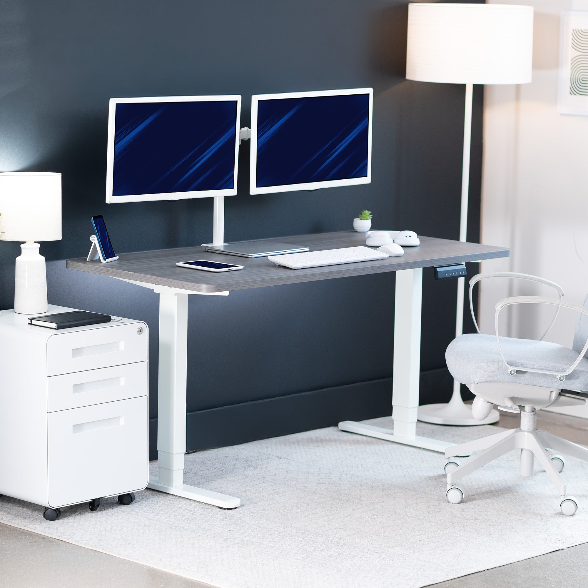 Modern office setup with a standing desk, computer monitors, and office chair.