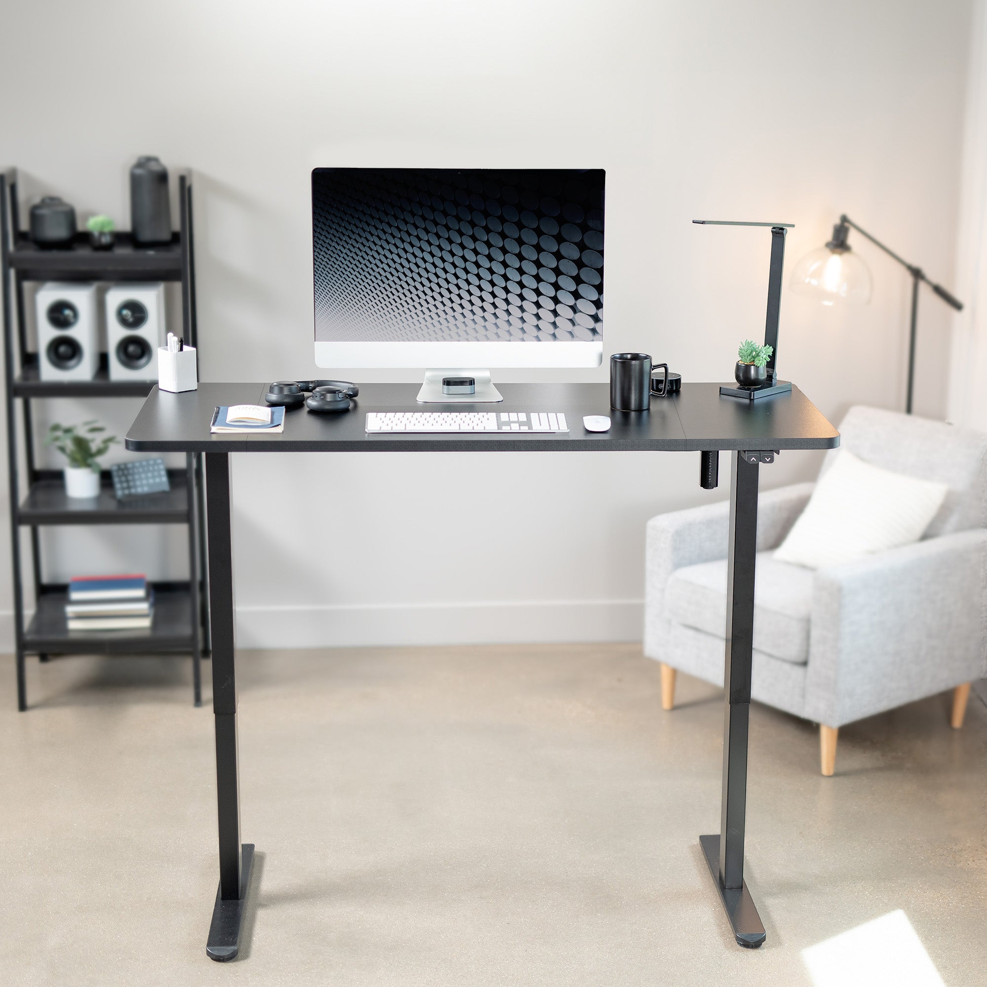 Modern home office with a adjustable desk, computer setup, and chair.