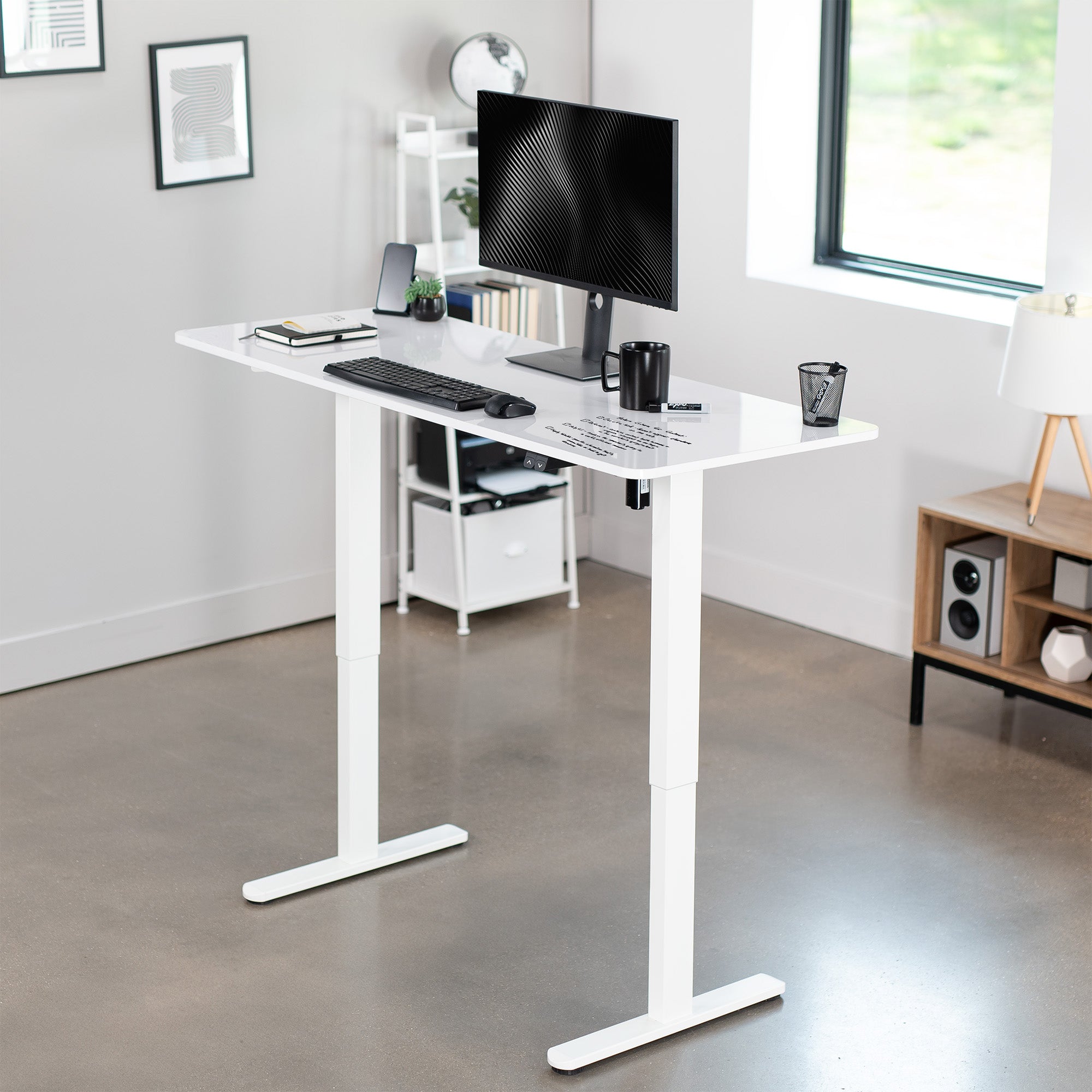 White adjustable desk with computer setup in a modern office.