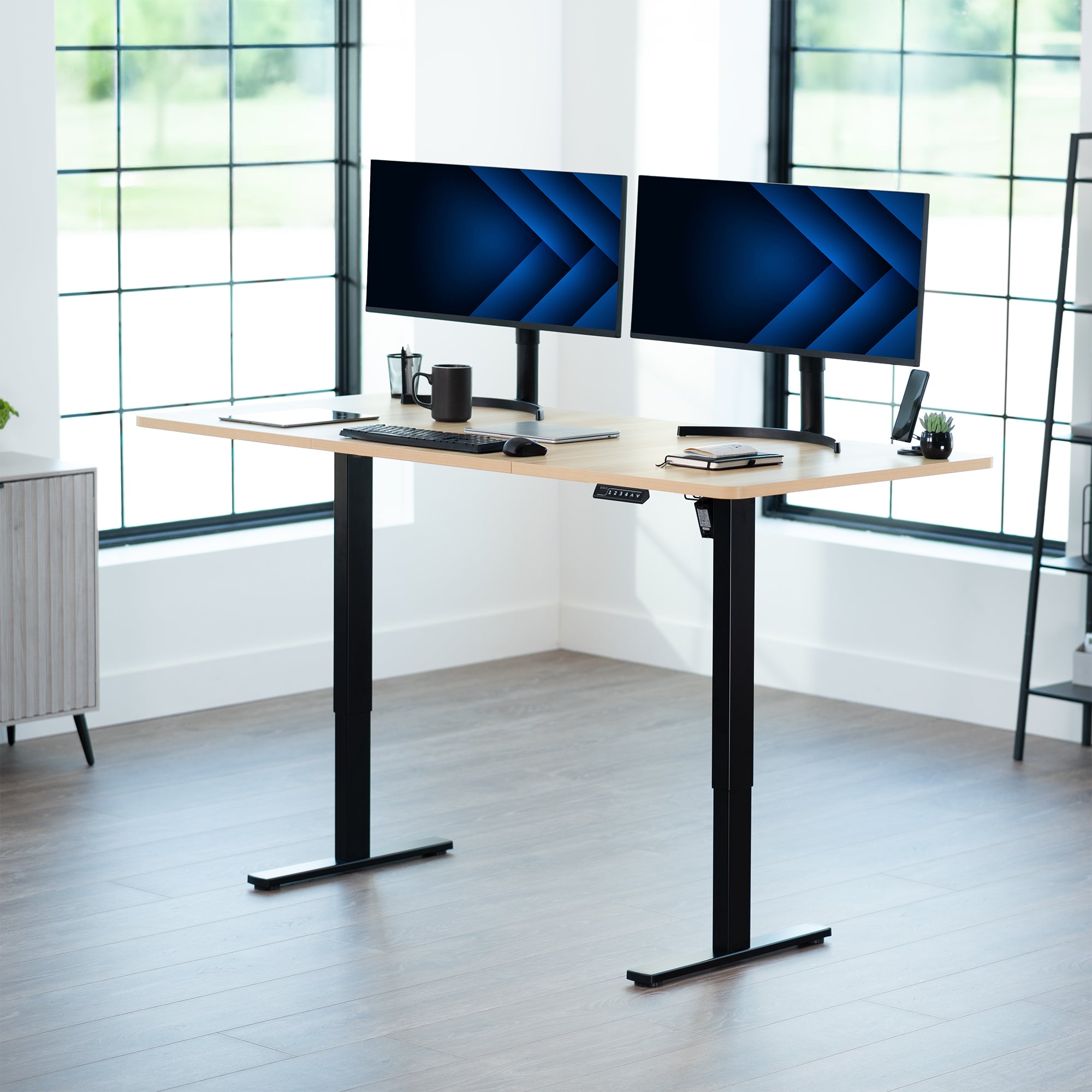 Modern office setup with a standing desk and dual monitors in a bright room.