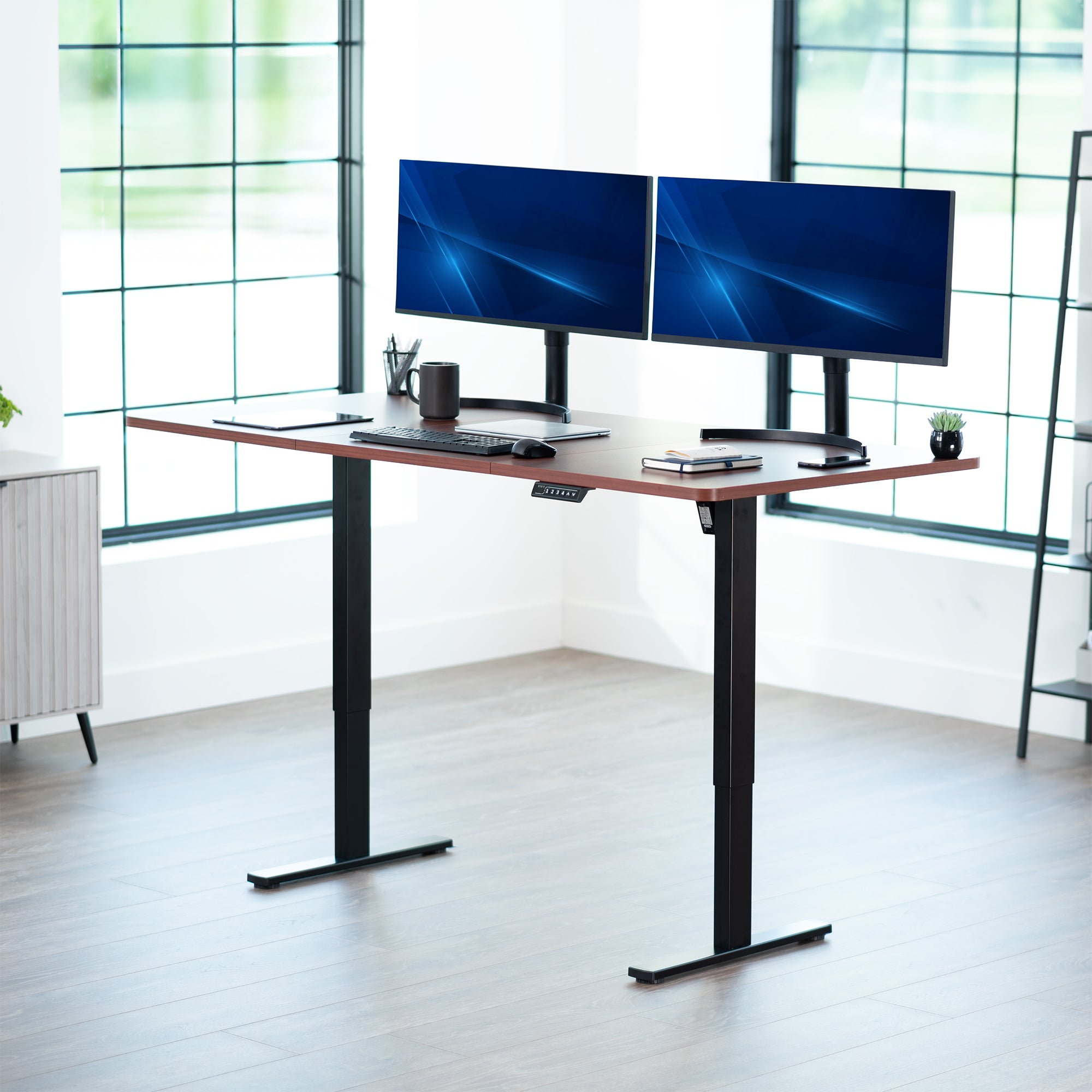 Modern office setup with a standing desk and dual monitors in a bright room.