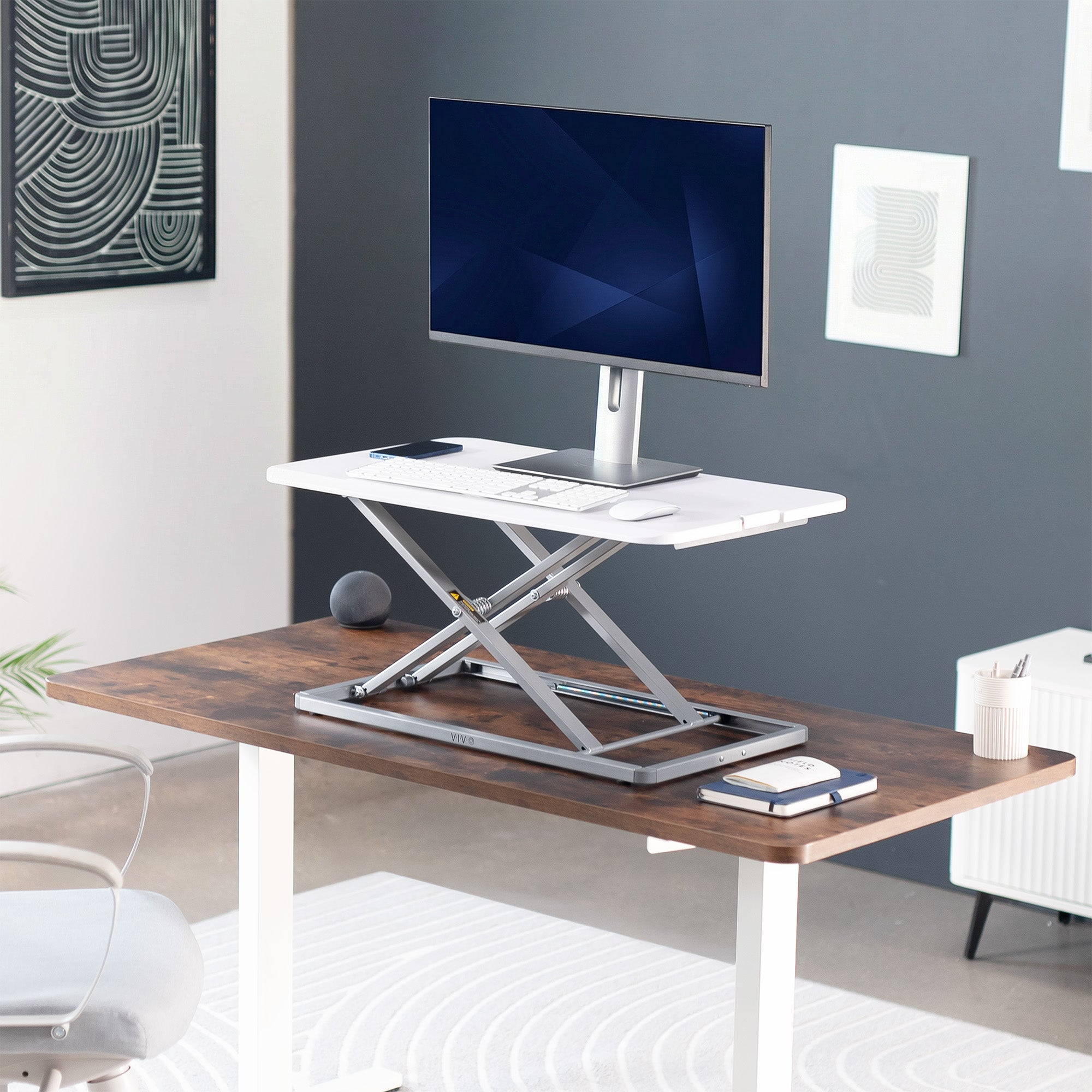 Sit stand desk converter with adjustable height, computer monitor, and office supplies in a home office setting.