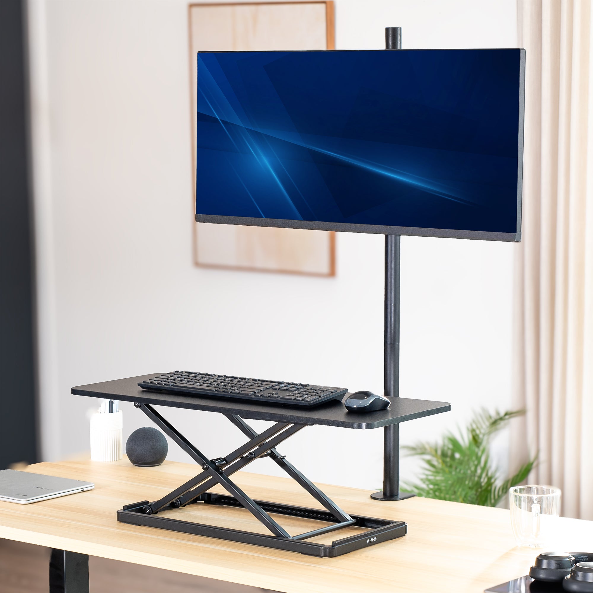 Riser desk with computer monitor, keyboard, and mouse on a wooden desk.