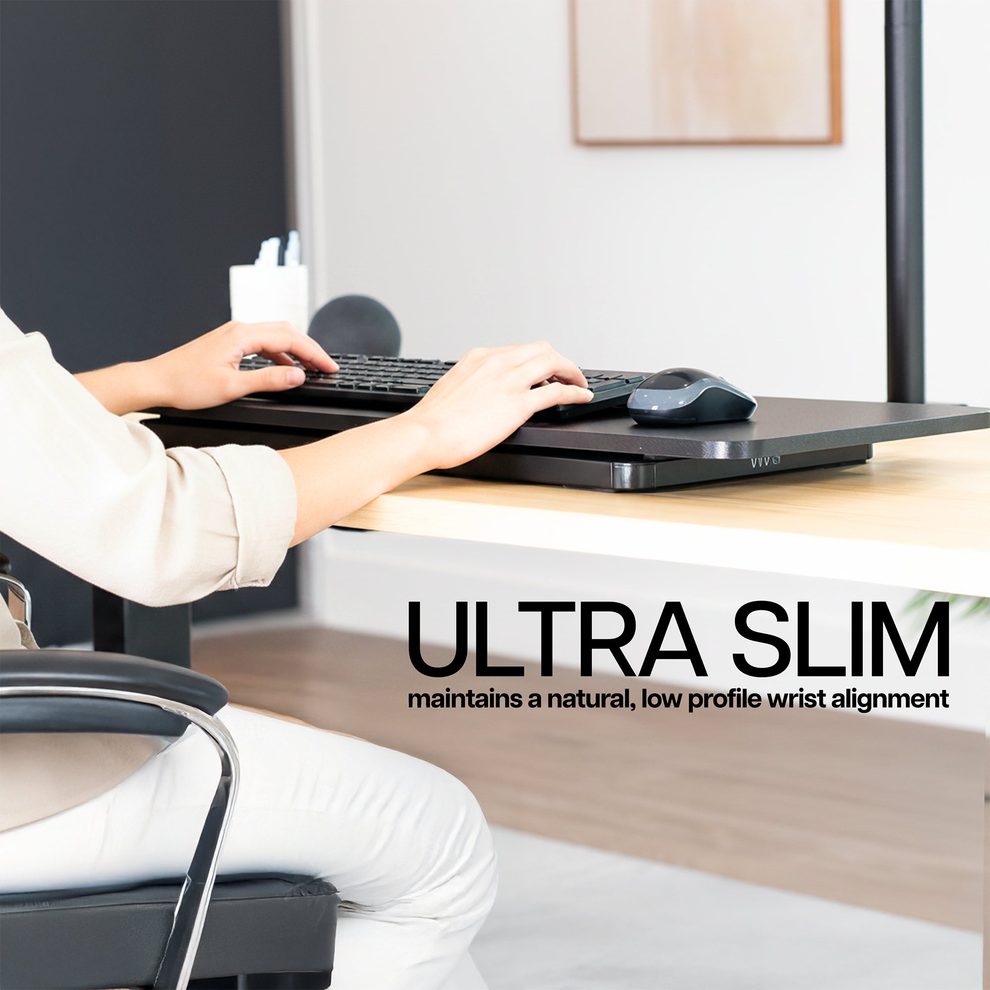 Person using a computer with an ultra slim keyboard on a desk, emphasizing comfort and design.