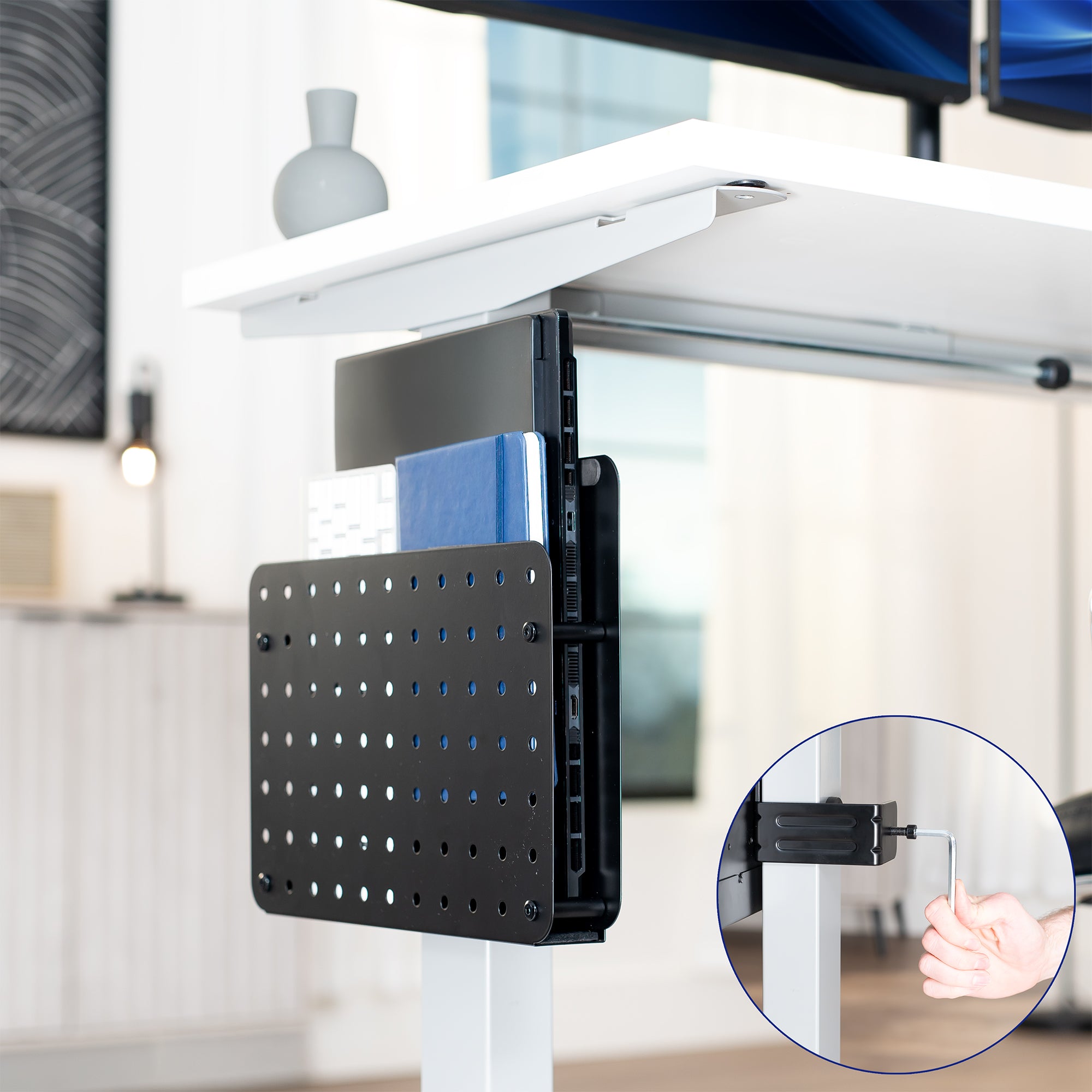 Steel Clamp-on Desk Leg Laptop Mount Holder on a white desk with a blurred office background