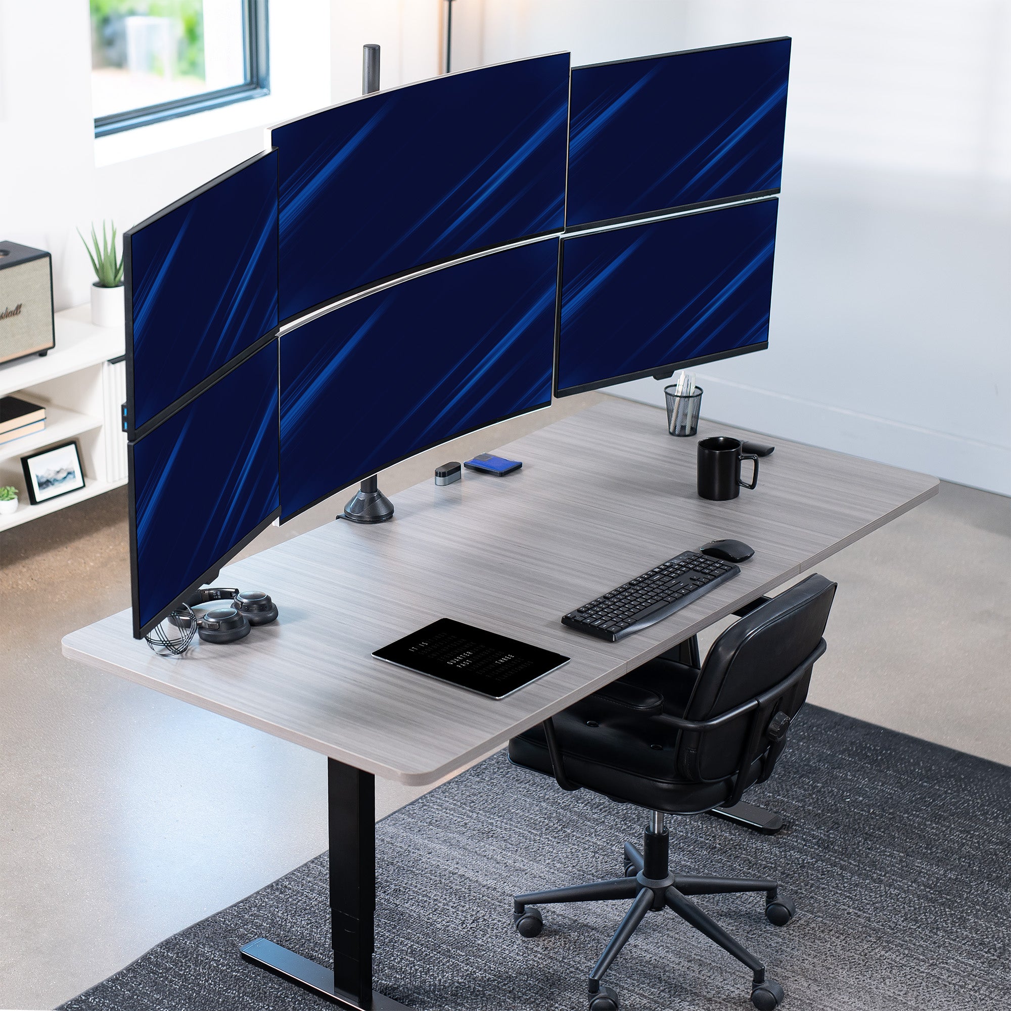 Modern office setup with a curved desk featuring four computer monitors, a keyboard, and mouse.