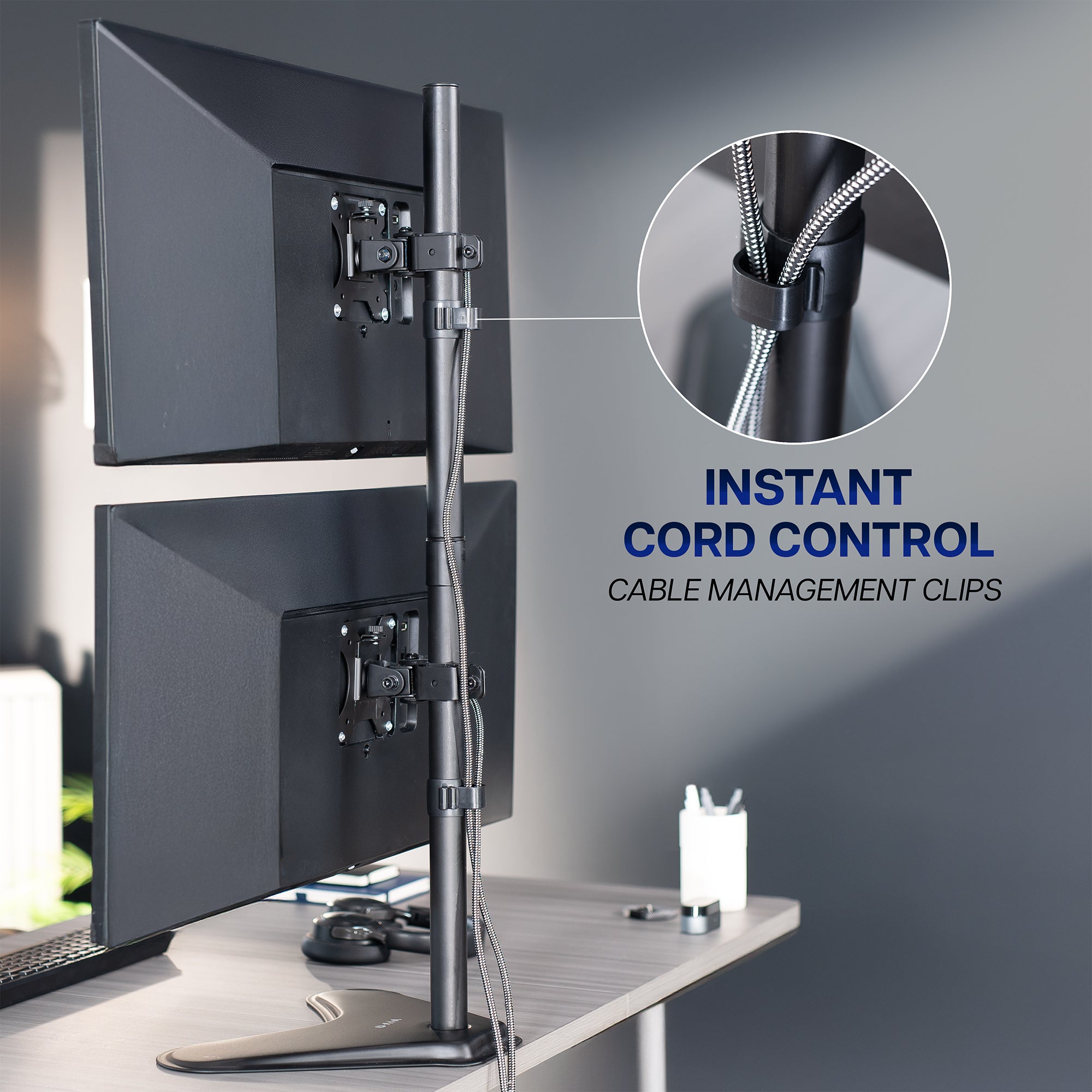 Monitor stand with cable management clips on a desk setup.