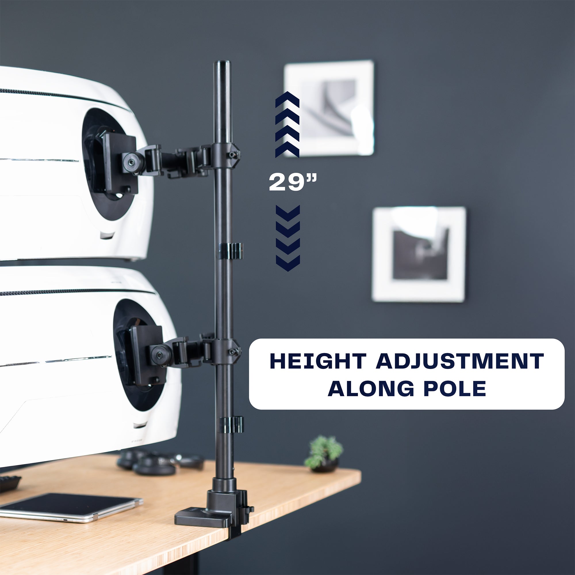 Height-adjustable stand with a phone mount on a desk against a dark wall.