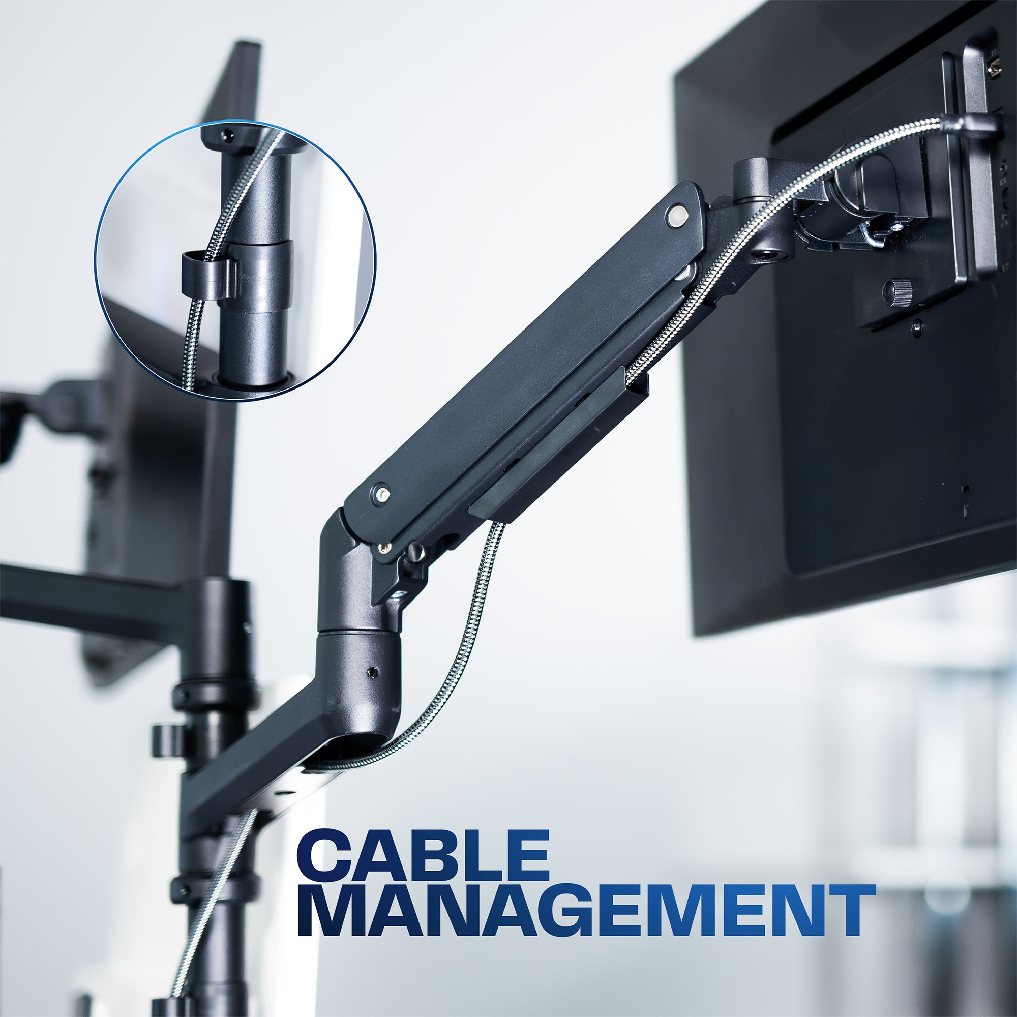 Close-up of a monitor arm with cable management feature in a blurred office setting.