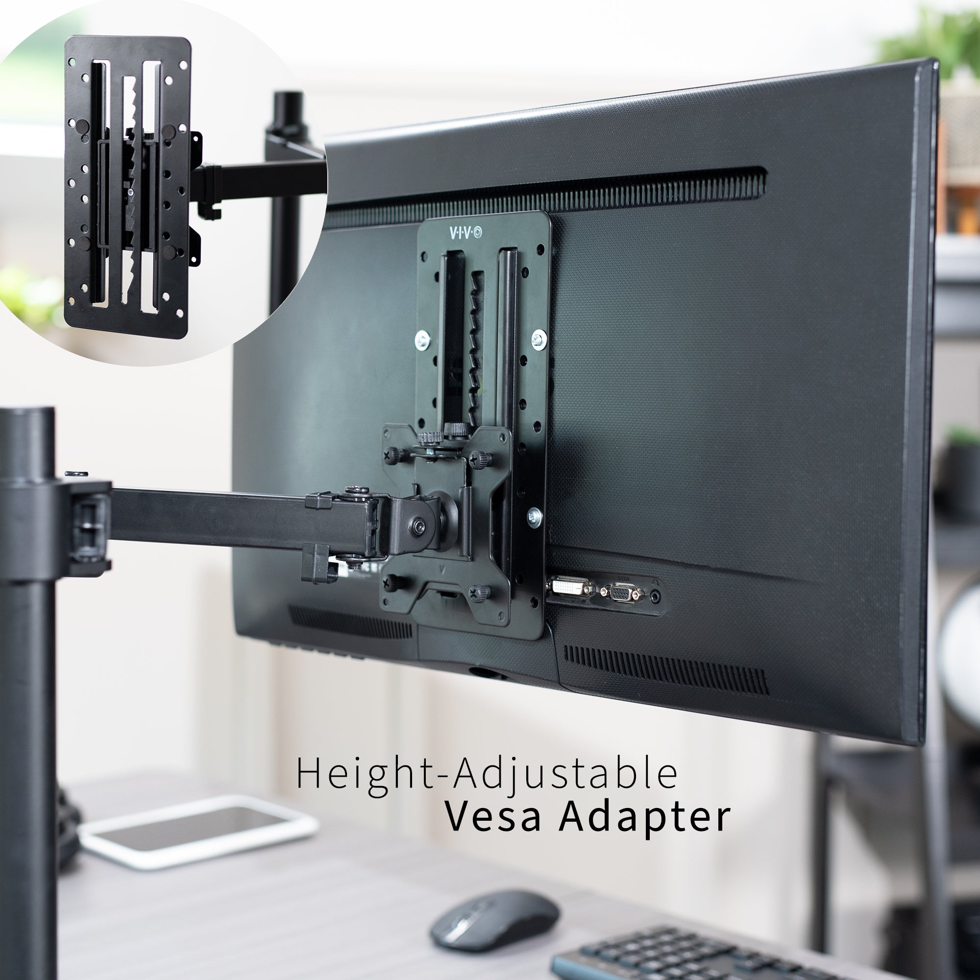 Height-adjustable Vesa adapter attached to a monitor on a desk with office background