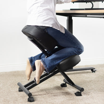 Ergonomic padded kneeling chair pulled up to an office desk.