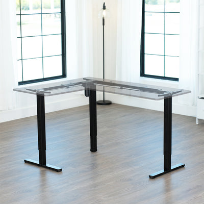 L-shaped adjustable desk in a bright room with large windows