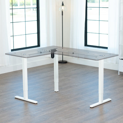 L-shaped desk with white, electric corner frame in a room with large windows.