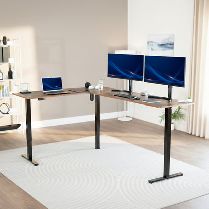 Modern office setup with a standing vintage brown l-shaped desk, laptop, and two monitors in a bright room.