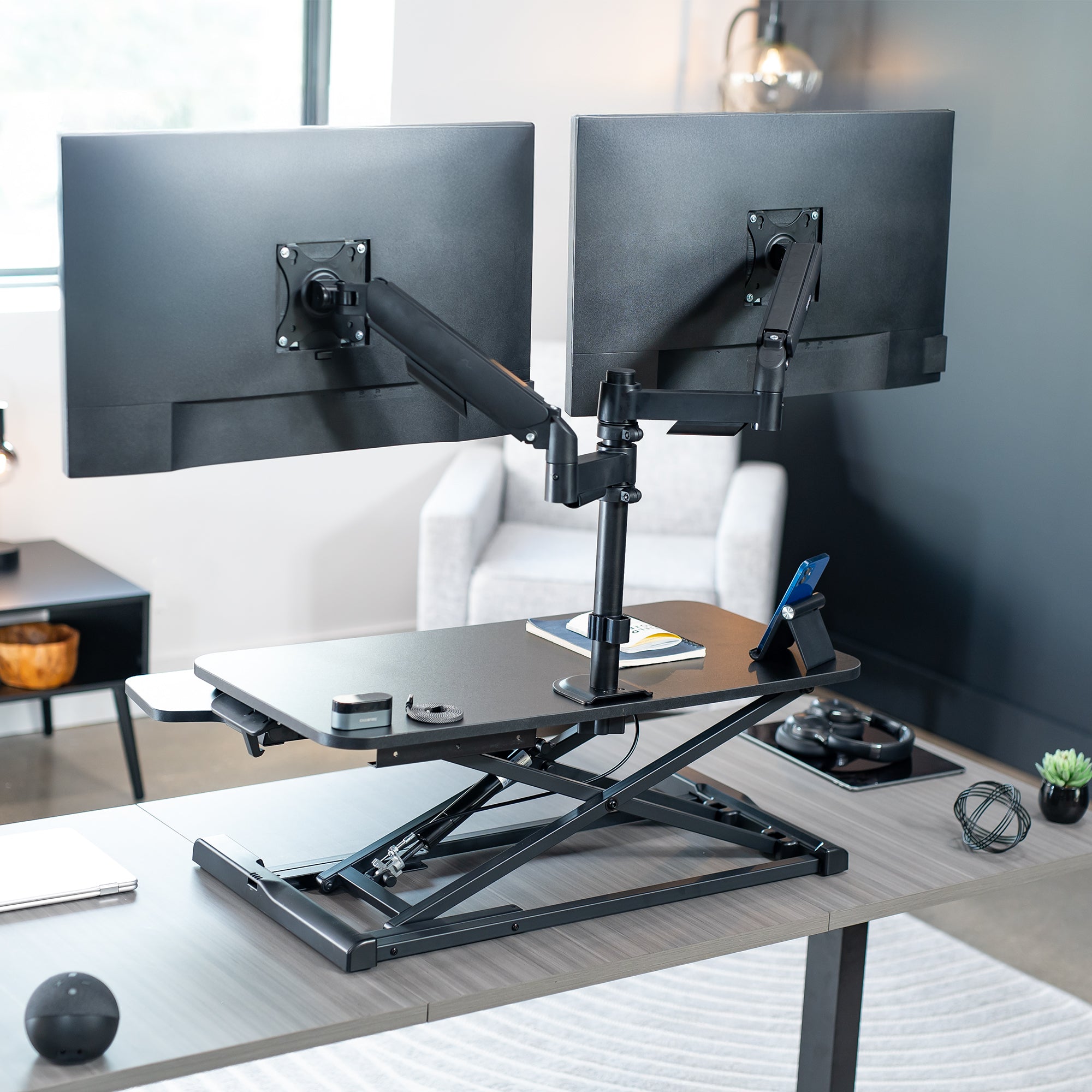 Height adjustable desk riser with articulating mechanical dual monitor mount.
