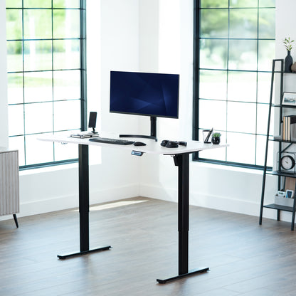 White, electric, sit to stand, height adjustable desk in office setting.