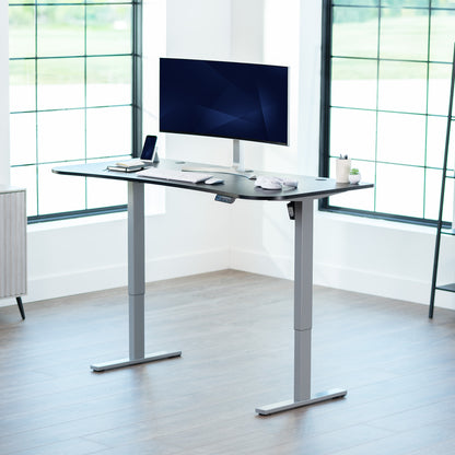 Black top grey frame, electric, sit to stand, height adjustable desk in office setting.