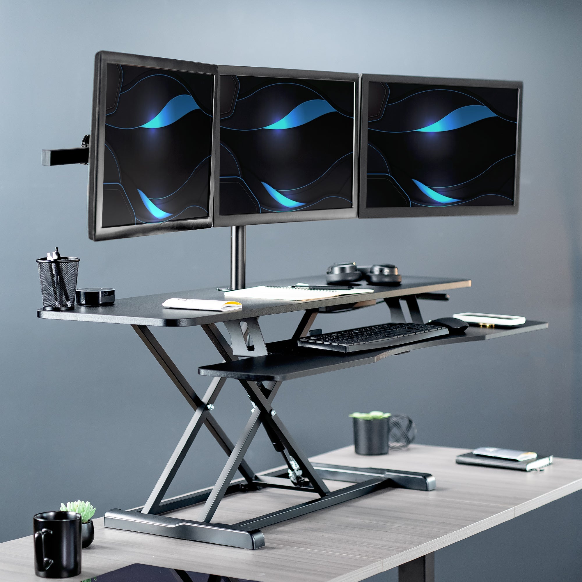 Spacious height adjustable desk riser with articulating triple monitor mount.