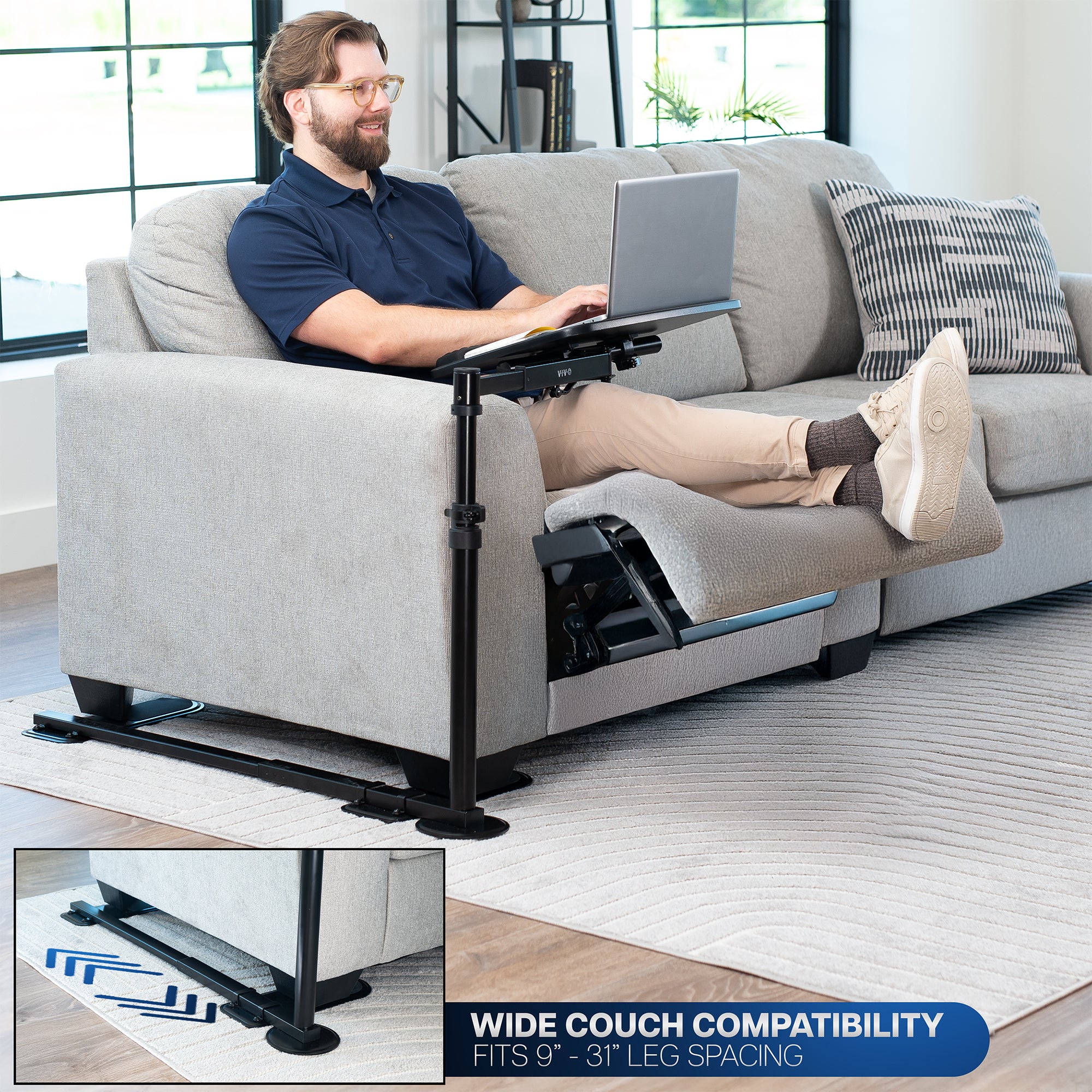 Man using a laptop on a couch with a portable laptop desk, surrounded by a modern living room.