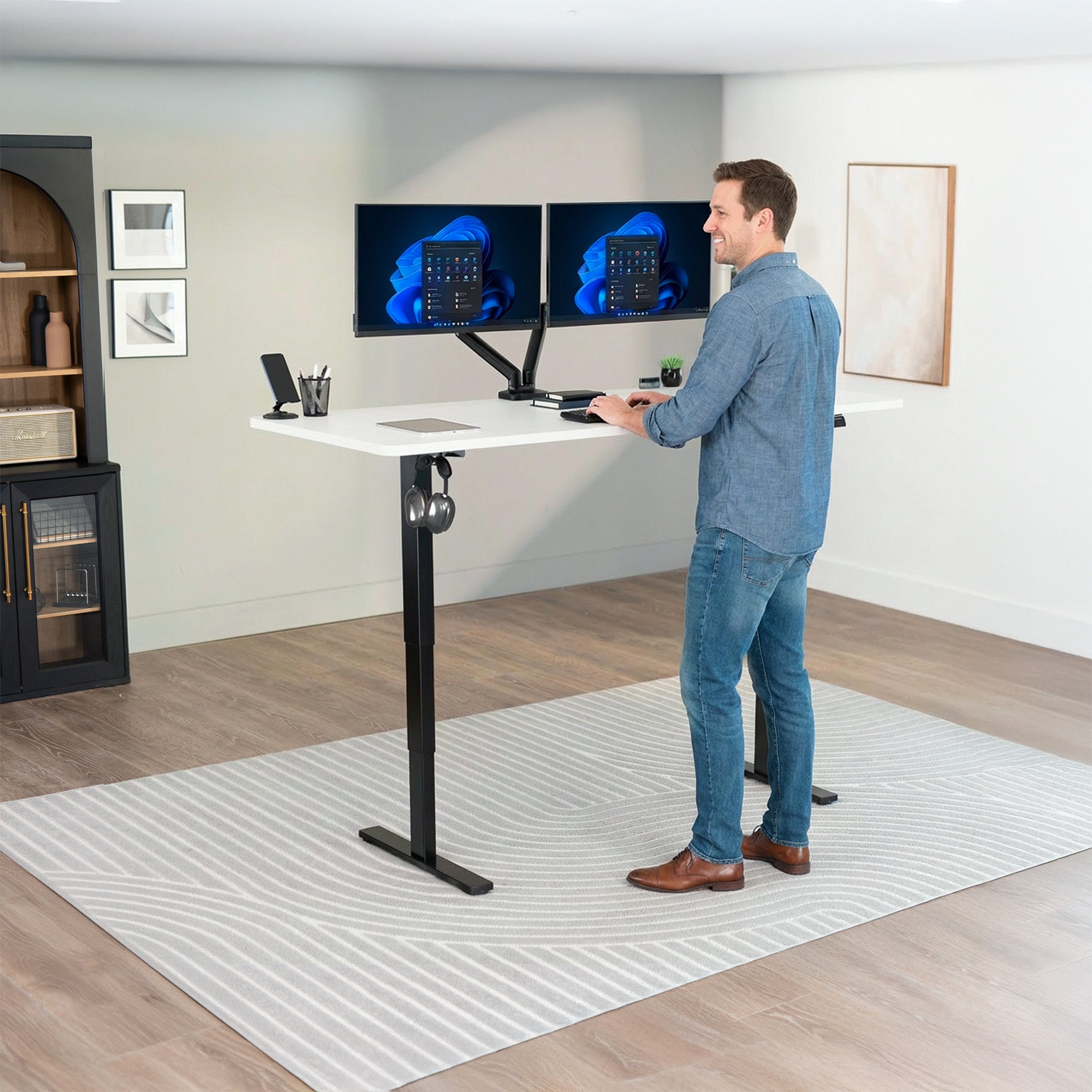 Man using a standing desk with multiple monitors in a home office setting.