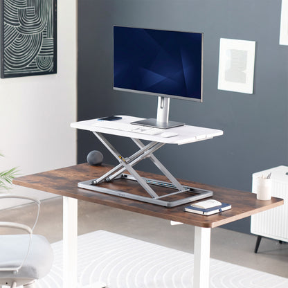 Sit stand desk converter with adjustable height, computer monitor, and office supplies in a home office setting.