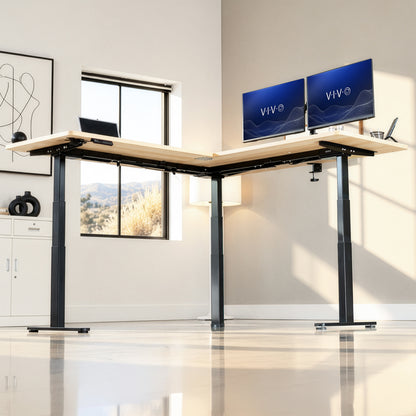 An L-shaped standing desk in a bright, modern home office. The desk has a light natural wood top and black metal legs, with two dual monitors displaying 'VIVO' on the right side.