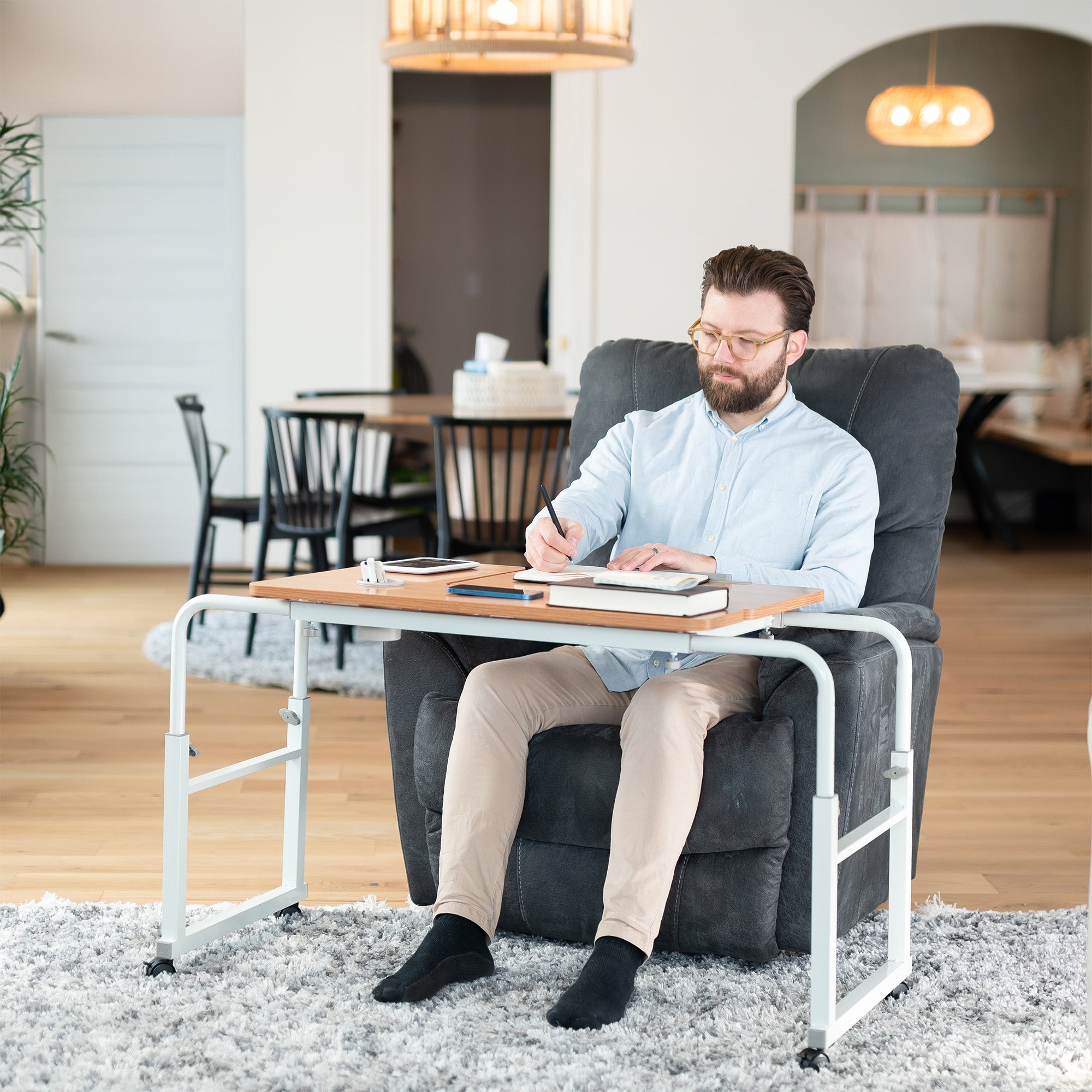Man sitting on a gray armchair with a desk in front of him, writing or working.