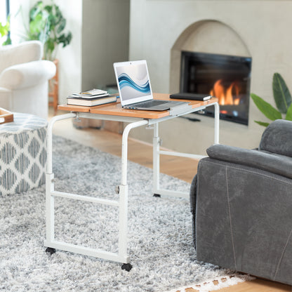 Laptop on a portable table in a living room with a fireplace and sofa.