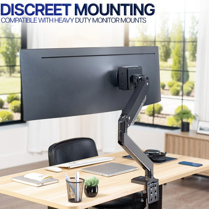 Monitor mount with Mac Mini mounted behind screen on a desk with a modern office background