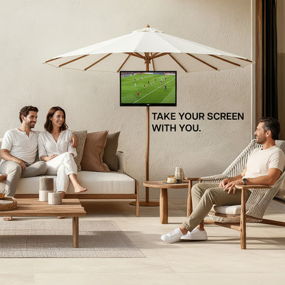 Two people sitting on a patio with a TV screen displaying sports, under a large white umbrella.