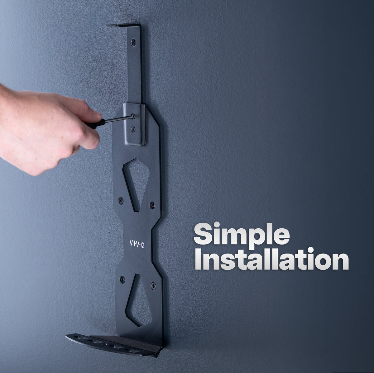 A hand using a screwdriver to install a dark gray metal wall mount bracket onto a textured gray wall, with the text 'Simple Installation' on the right.