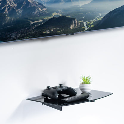 Modern look tempered glass floating shelf with sturdy steel frame installed below a TV.