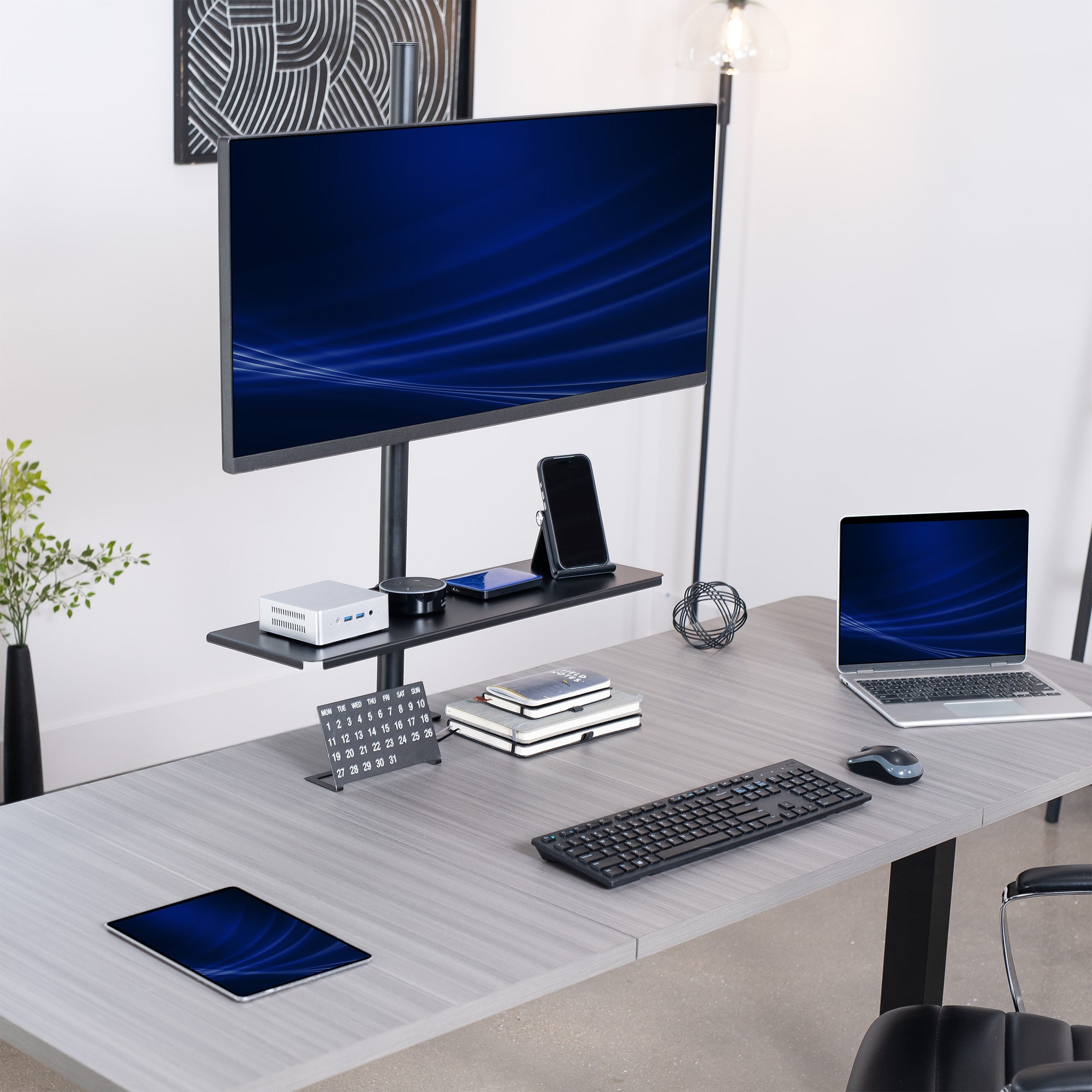 Modern office desk setup with a Clamp-on Shelf Pole Mount, computer monitor, laptop, keyboard, and tablet