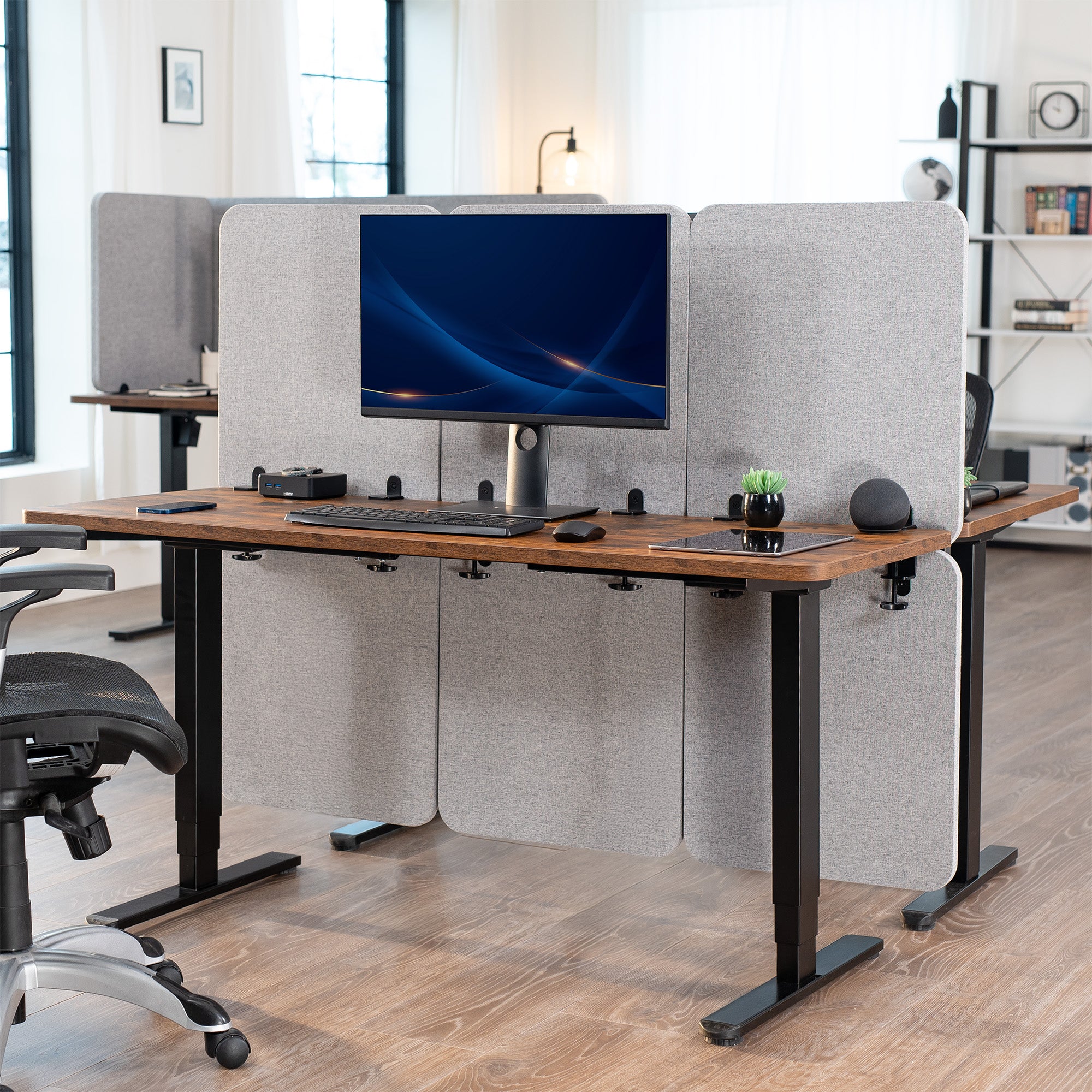 Modern office setup with a standing desk, computer monitor, and office chairs.