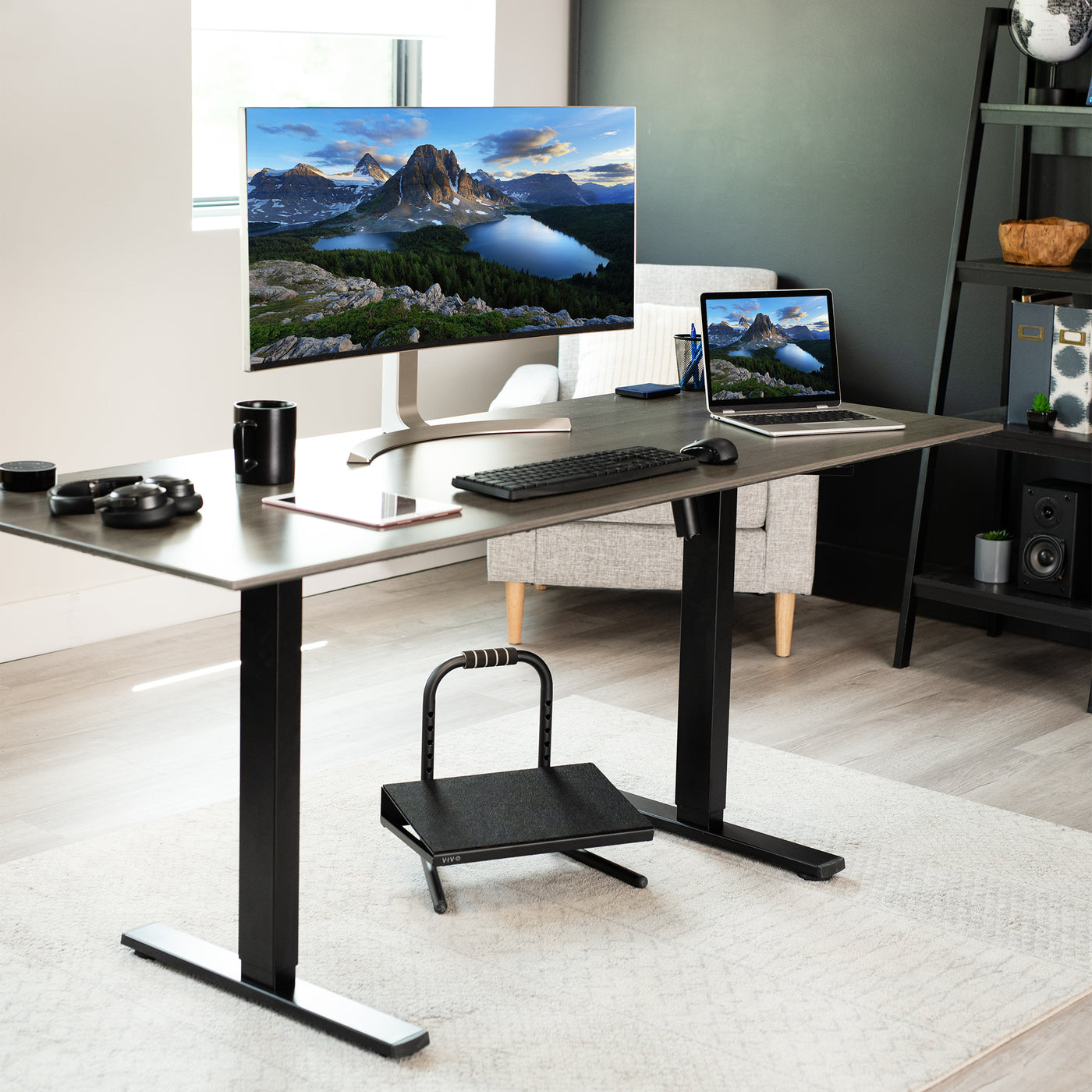 Black footrest under an electric desk in a modern workspace.