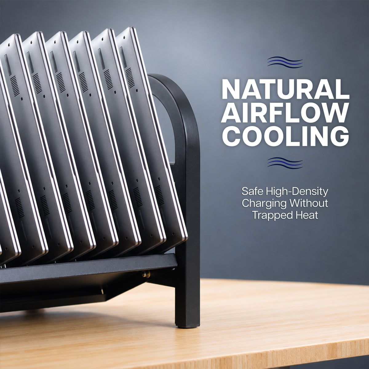 A black metal laptop rack holding multiple silver laptops on a light wood tabletop against a dark gray background, with text reading 'NATURAL AIRFLOW COOLING' and 'Safe High-Density Charging Without Trapped Heat'.