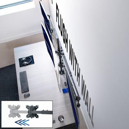 Computer monitor mount attached to a wall with desk and keyboard in the background
