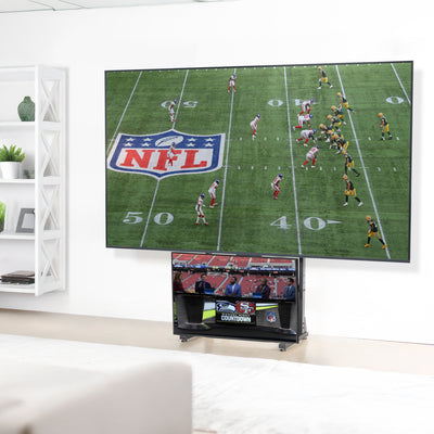 A large flat-screen television mounted on a heavy-duty floor stand with a football game on the screen. 