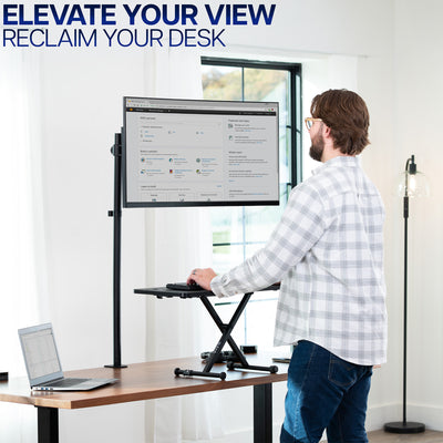 Man using a standing keyboard desk riser and extra tall monitor stand in a home office setting with text 'Elevate Your View, Reclaim Your Desk'.